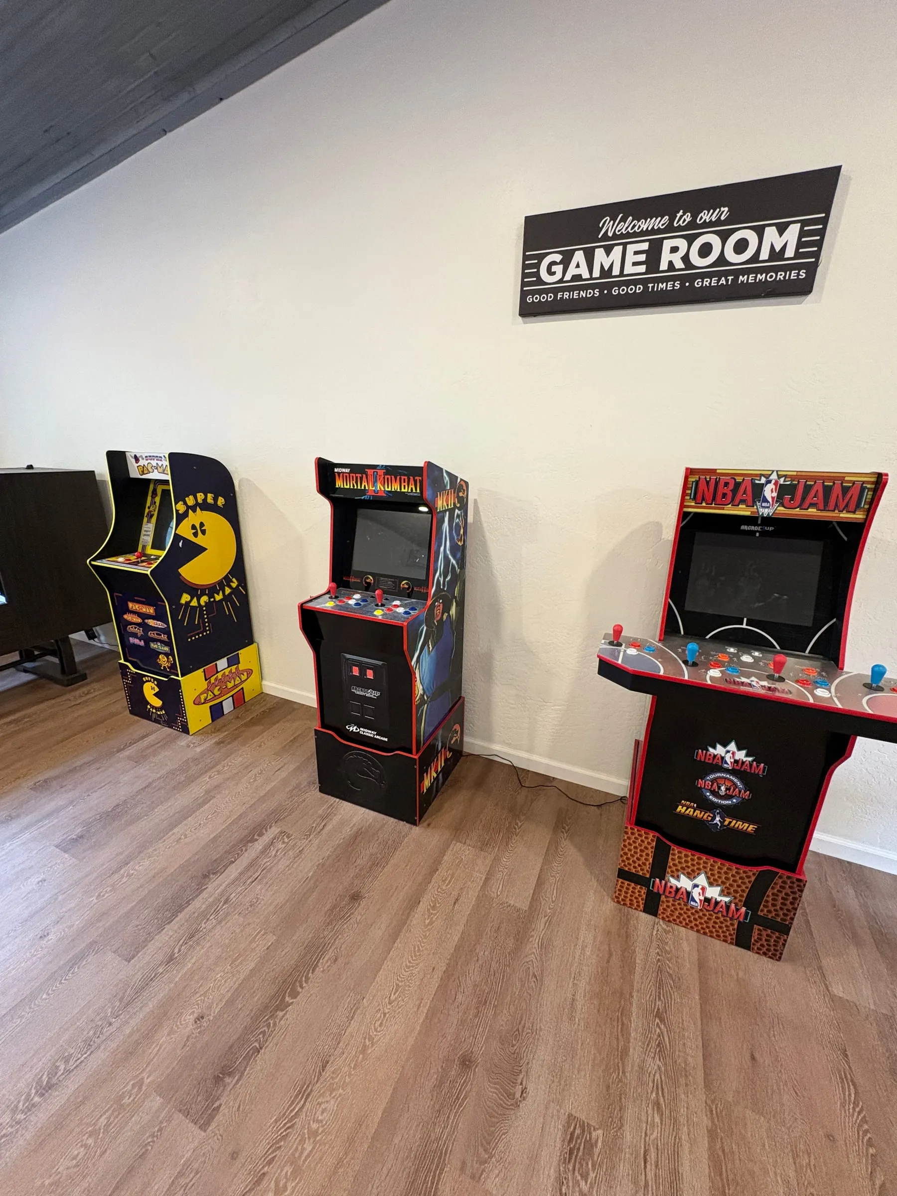 Three stand-up arcade cabinets against the wall under a Game Room sign — Super Pac-Man, Mortal Kombat, and NBA Jam. Each one holds several games.
