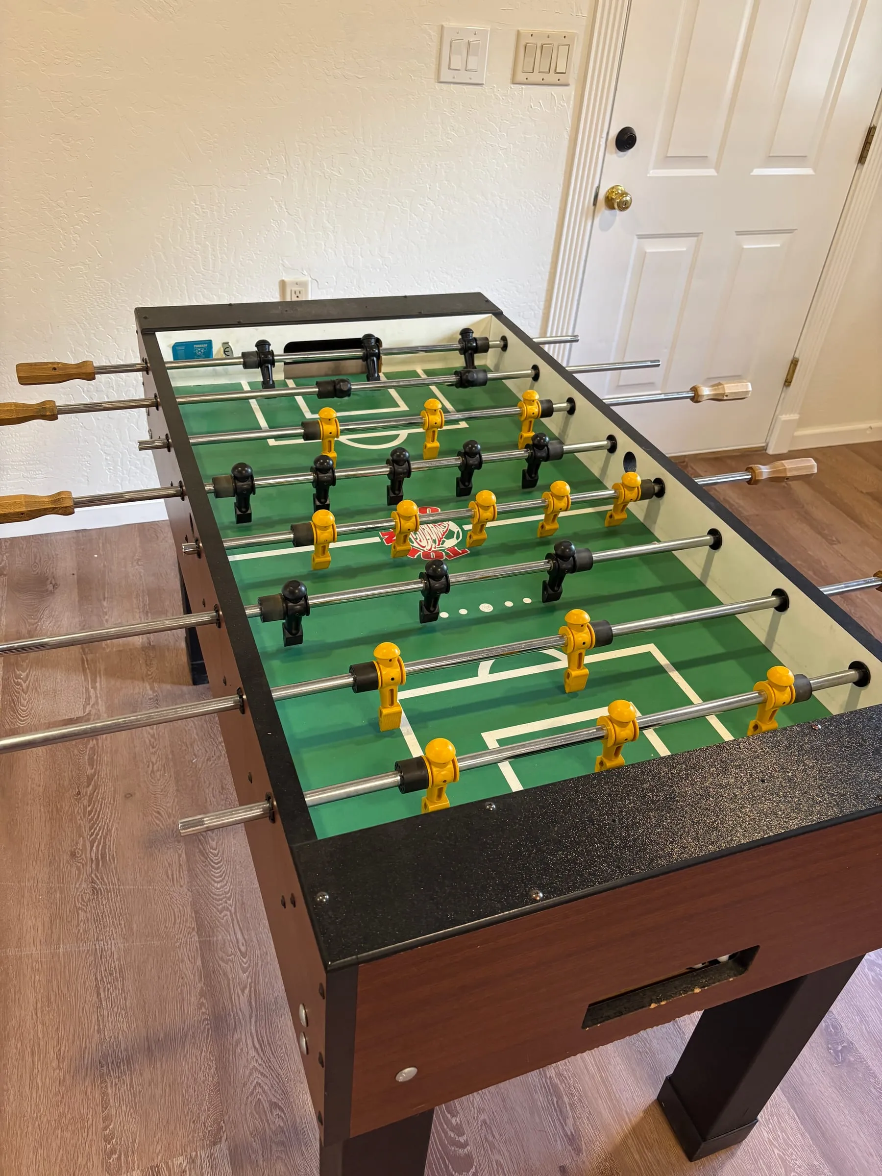 A full-size foosball table with wooden handles, set up for a game.