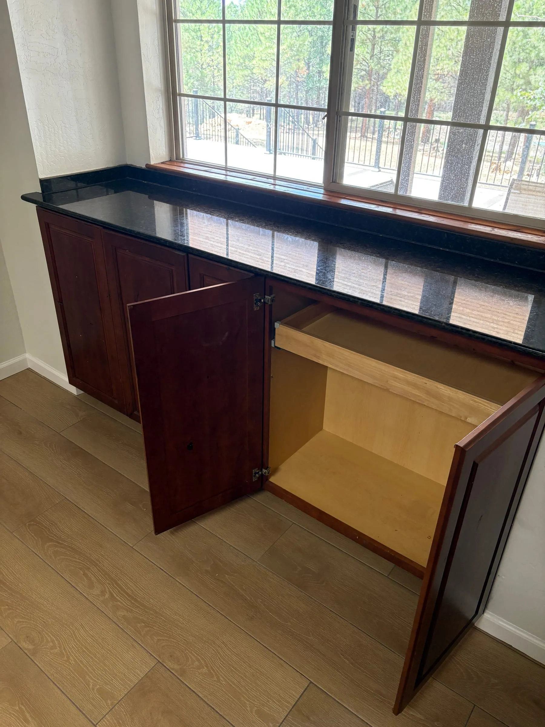 An empty kitchen cabinet standing open below the counter, cleared out and kept free for guests to store their own food and snacks.