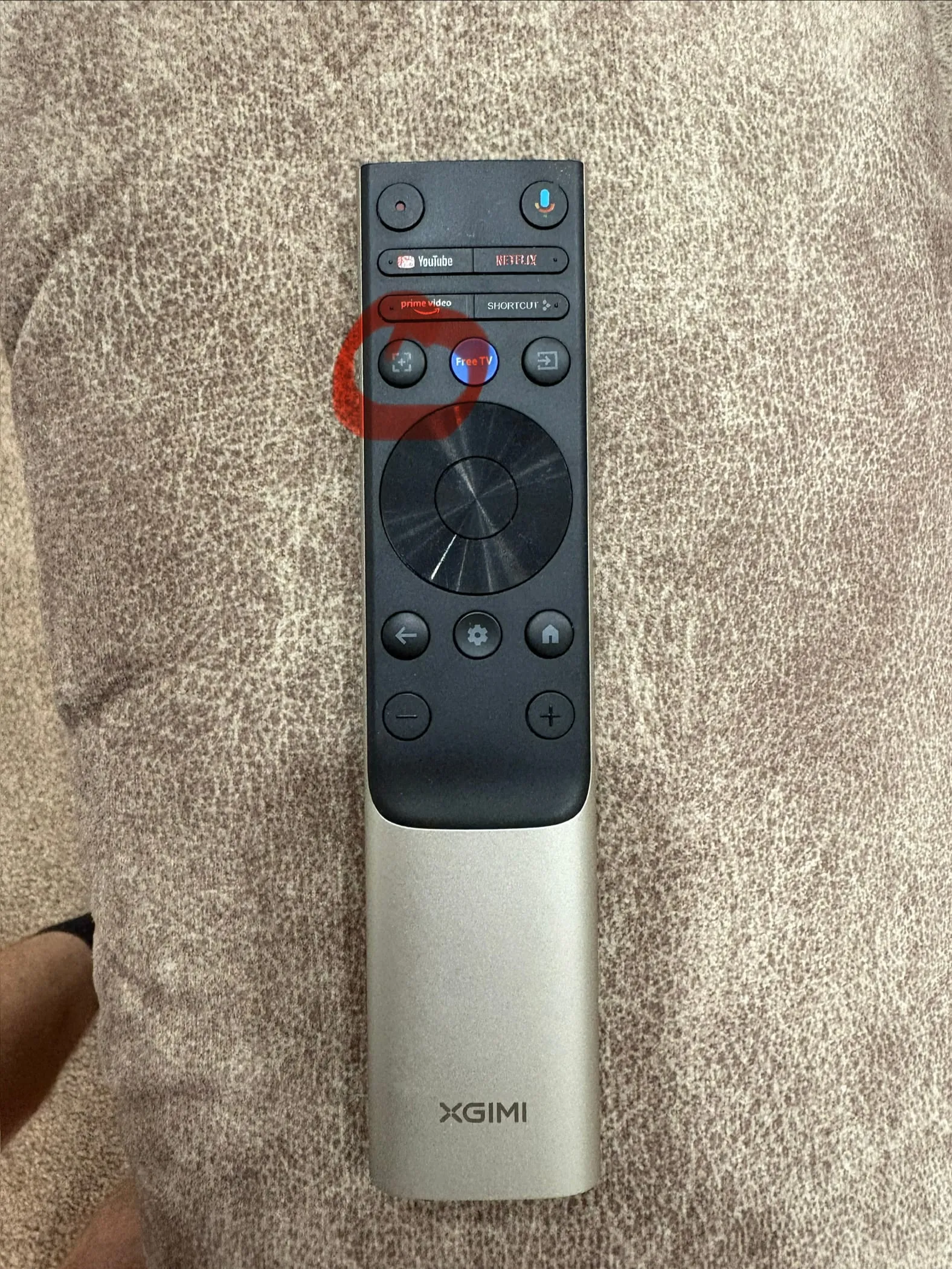 The projector remote, with the focus button circled in red. It is the square button on the left of the row just above the round pad.